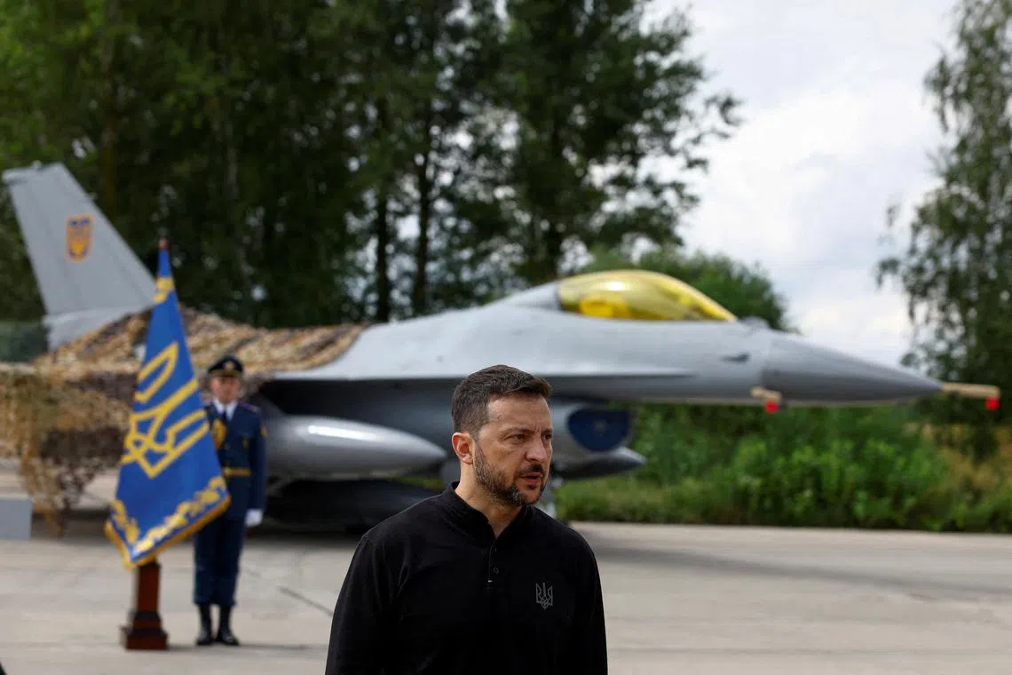 FILE PHOTO: Ukraine's President Volodymyr Zelenskiy speaks to the media in a front of an F-16 fighter jet on the Day of the Ukrainian Air Forces, amid Russia's attack on Ukraine, at an undisclosed location, Ukraine August 4, 2024. REUTERS/Valentyn Ogirenko/File Photo