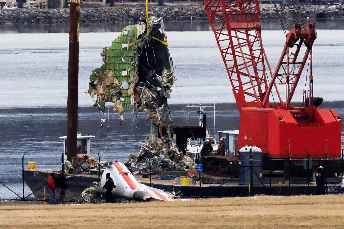 A barge carrying a crane move parts of the wreckage from the Potomac River, in the aftermath of the collision of American Eagle flight 5342 and a Black Hawk helicopter that crashed into the river, by the Ronald Reagan Washington National Airport, in Arlington, Virginia, U.S., February 5, 2025.  REUTERS/Eduardo Munoz