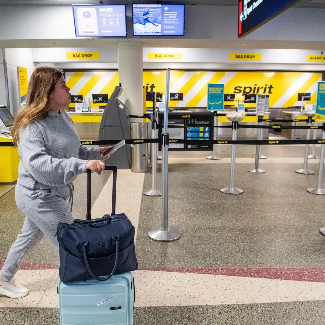 A passenger makes her way near an empty bag drop and customer service counters for Spirit airlines at Logan Airport in Boston.

