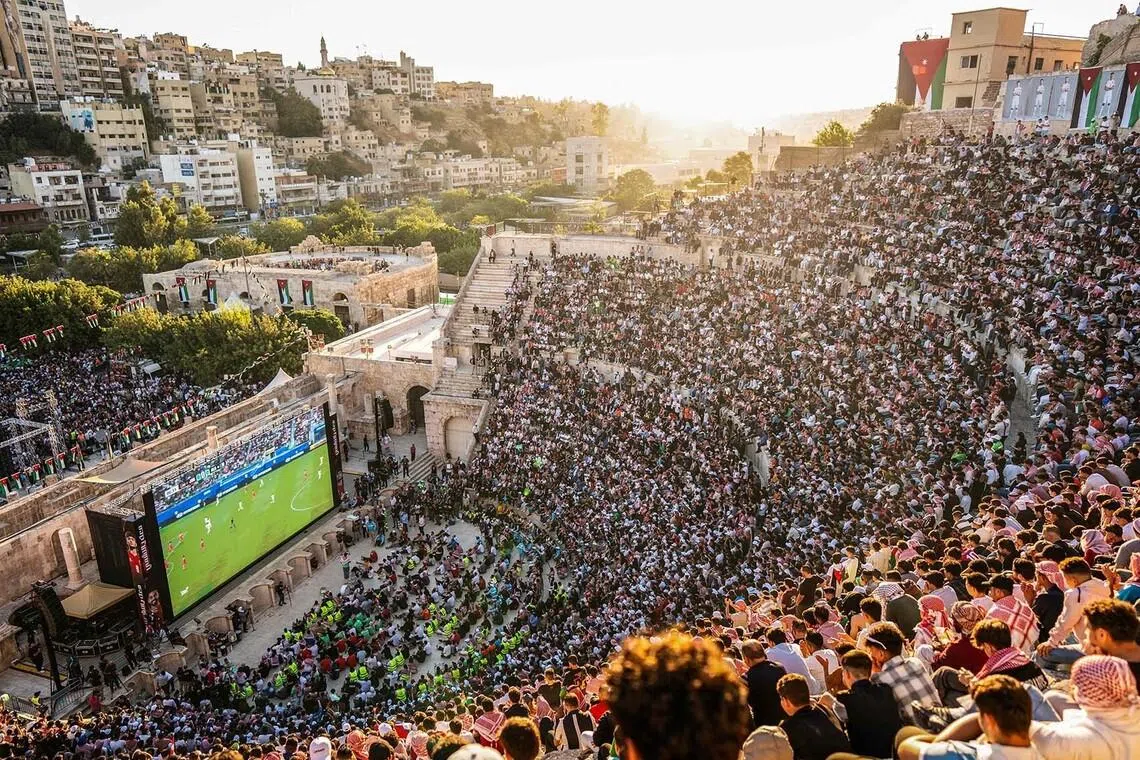Jordanian football fans gathering to watch on giant screens their national team's World Cup football match against Algeria at Amman's 2nd-century Roman amphitheatre early on June 23. 