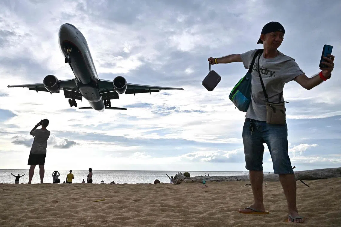 A tourist taking a selfie at Thailand's Mai Khao Beach as a plane lands at Phuket International Airport on Nov 18, 2023.