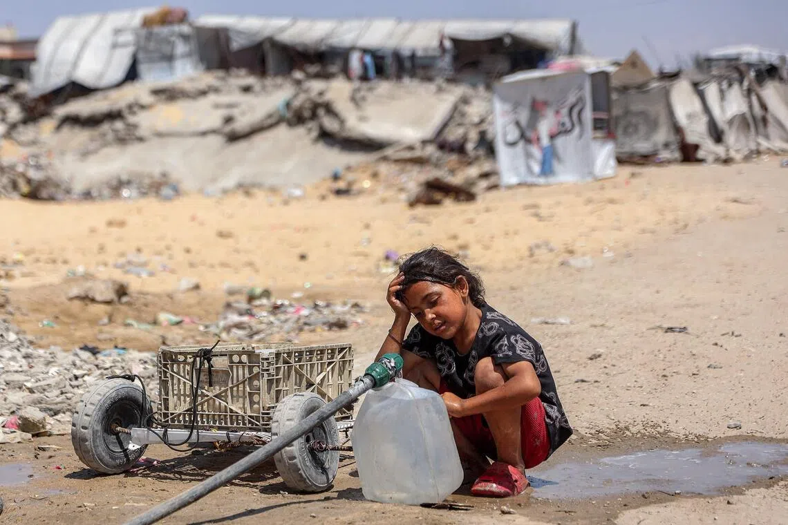 A girl fills containers with water drawn from the leftovers of underground pipes at a camp for people displaced by war in Gaza City.