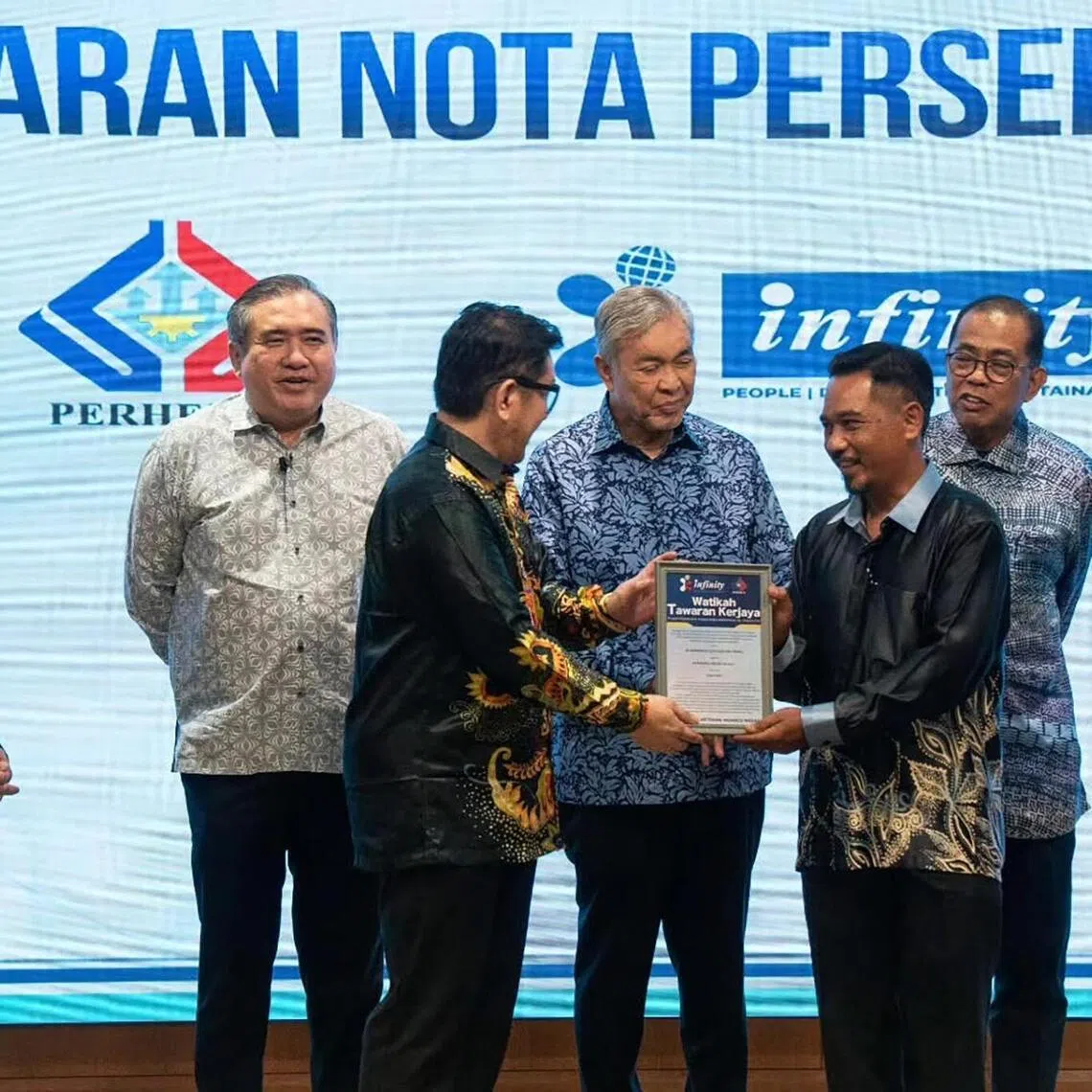 Deputy Prime Minister Zahid Hamidi (centre, dark blue batik) witnesses Infinity Logistics & Transport Sdn Bhd present a job offer letter to a successful veteran applicant.