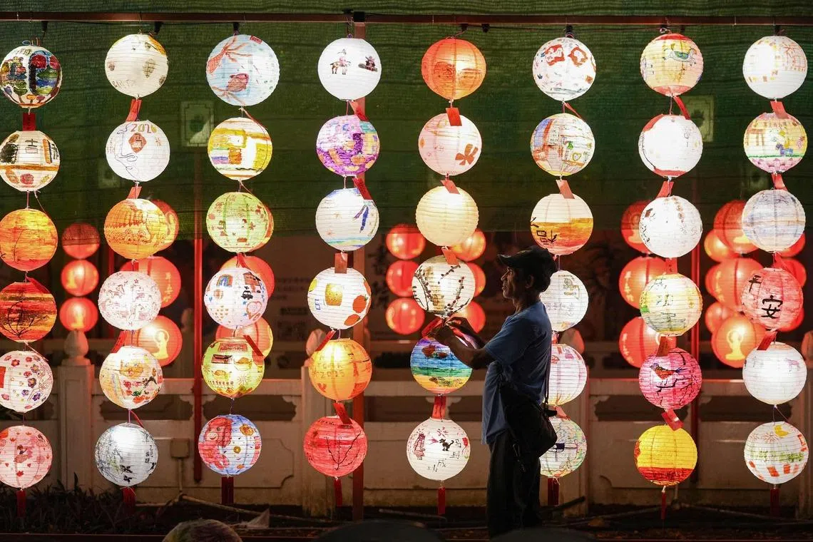 A worker hanging illuminated lanterns during the Lanterns and Flora Festival at the Fo Guang Shan Dong Zen Temple ahead of the upcoming Lunar New Year of the Horse in Jenjarom, Malaysia's Selangor state on Feb 10, 2026. 