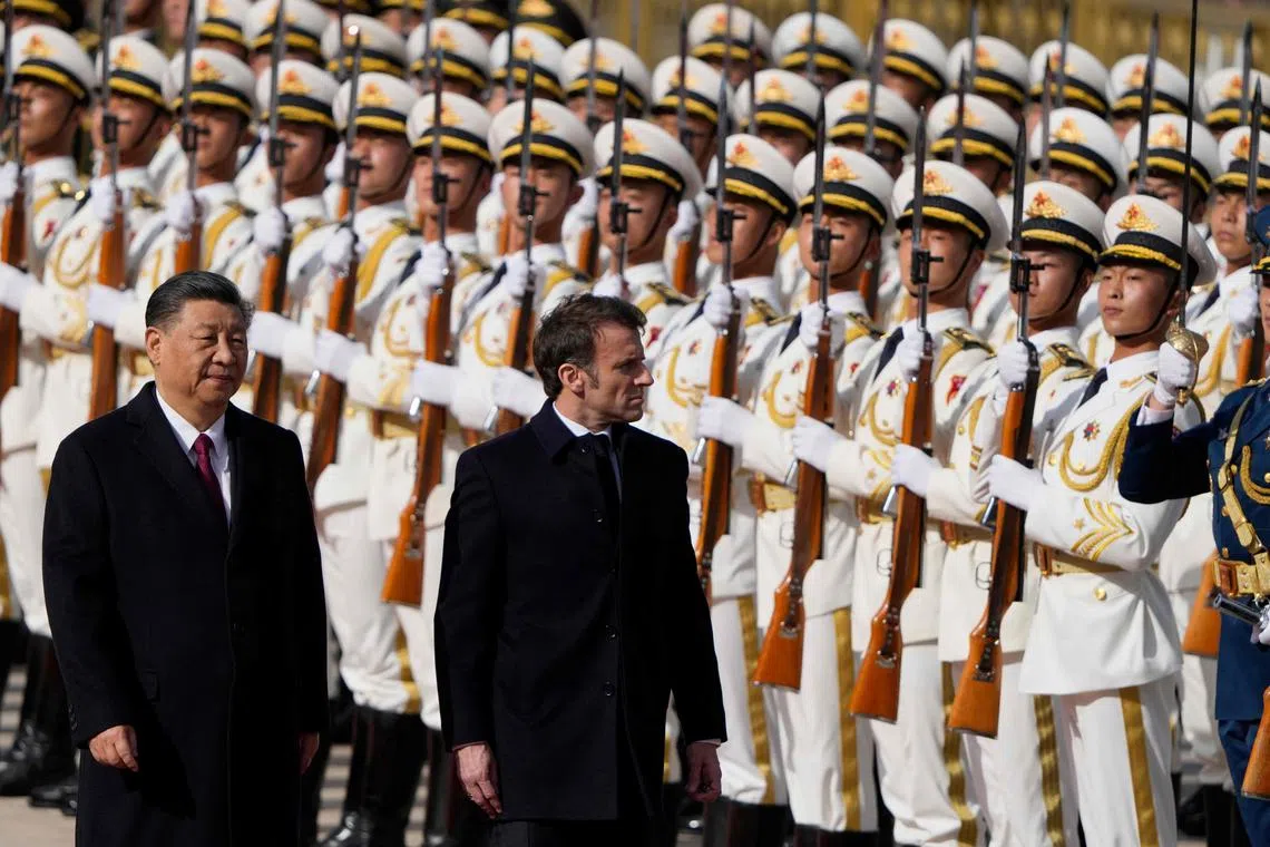 China's President Xi Jinping (L) and his French counterpart Emmanuel Macron review a honour guard during the official welcoming ceremony in Beijing on April 6, 2023. (Photo by Ng Han Guan / POOL / AFP)