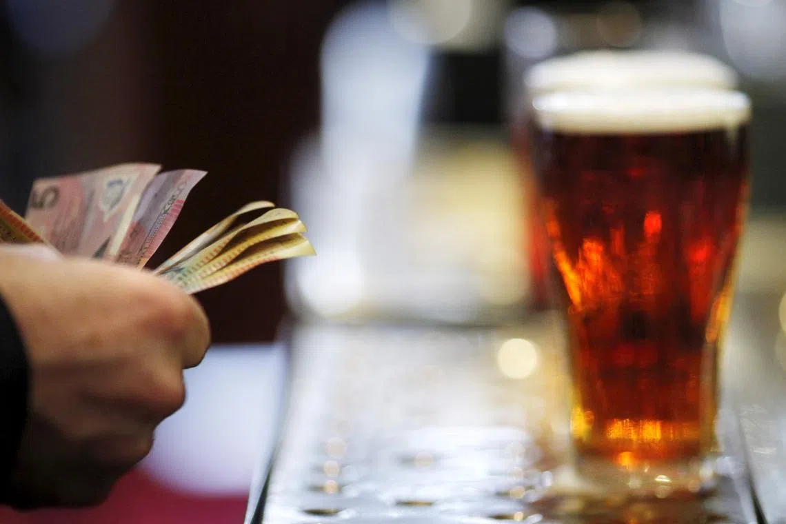 FILE PHOTO: A customer pays for a Fosters beer at the Occidental Hotel in central Sydney in this June 21, 2011 file photo. REUTERS/Tim Wimborne/File Photo