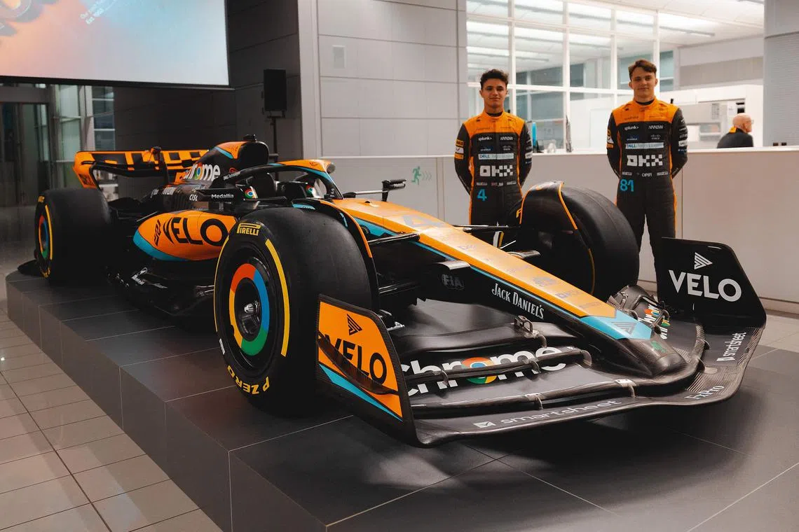 British driver Lando Norris (left) and Australian rookie Oscar Piastri posing beside the McLaren MCL60 Formula One racing car for the 2023 season at their base in Woking, west of London.