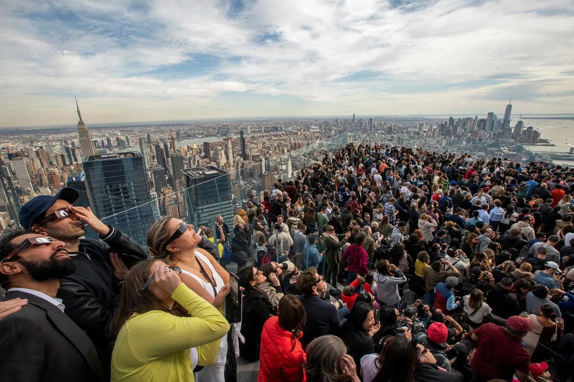 People watching the solar eclipse from the observation deck of Edge at Hudson Yards in New York City on April 8, 2024. 