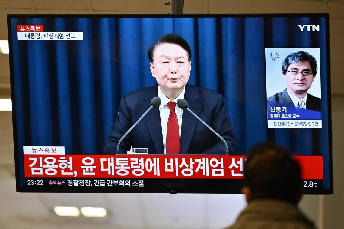 A man watches South Korea's President Yoon Suk Yeol speak during a news broadcast on a television at a train station in Seoul on Dec 3, 2024.