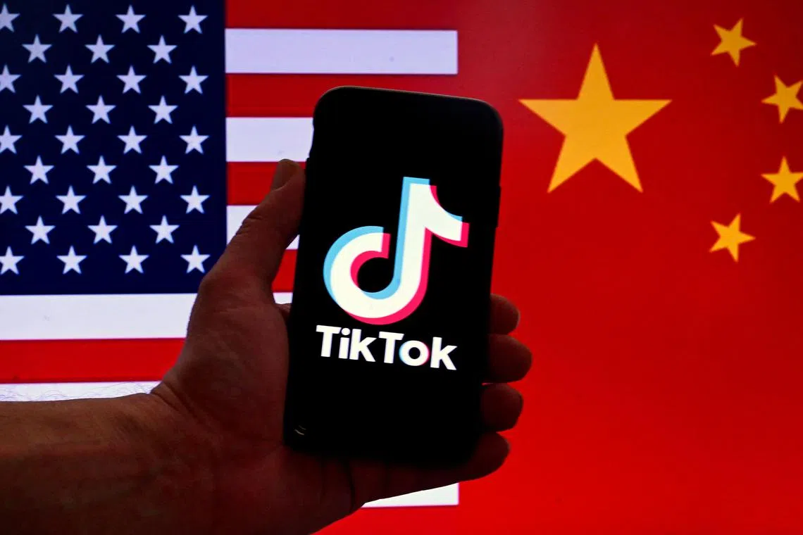 (FILES) In this photo illustration the social media application logo for TikTok is displayed on the screen of an iPhone in front of a US flag and Chinese flag background in Washington, DC, on March 16, 2023. China on March 14, 2024 slammed the approval of a US bill that would ban TikTok unless it severs ties with its Chinese parent company, blasting Washington's "bandit" mentality and vowing Beijing would "take all necessary measures" to protect the interests of its companies overseas. (Photo by OLIVIER DOULIERY / AFP)
