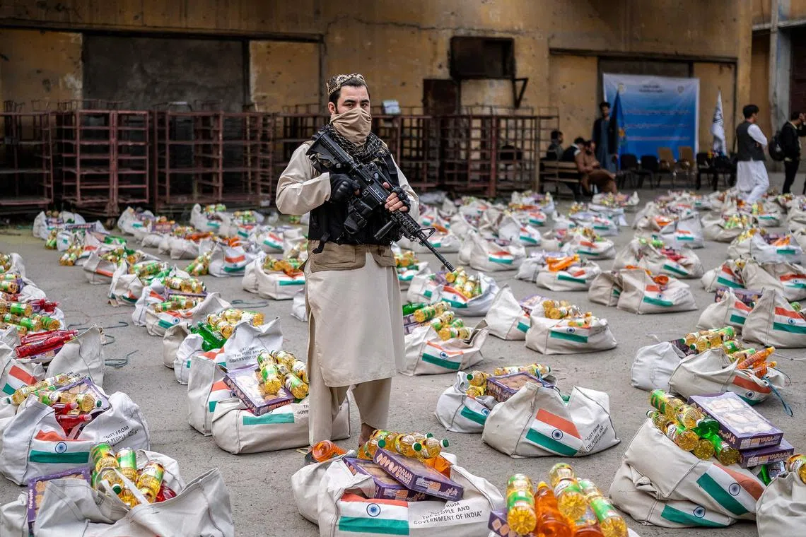 A Taliban security personnel stands guard next to the sacks of food aid donated by the Indian government in Kabul on May 18.