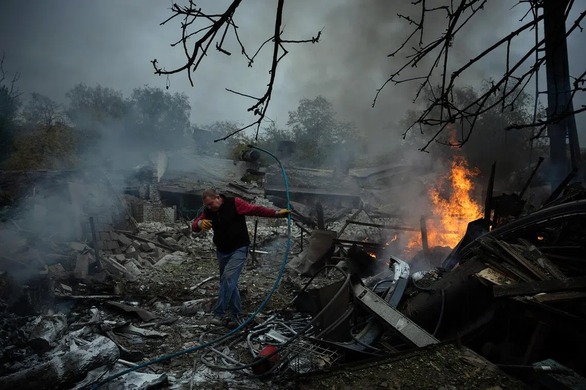 A man making his way past burning wreckage following a Russian drone attack in Slovyansk, eastern Ukraine, on Oct 9.