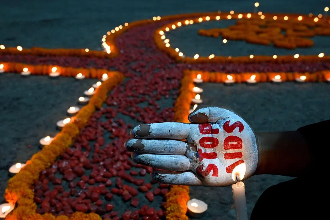 A social activist paints his palm with ‘Stop AIDS’ message during an awareness campaign organised to observe ‘World AIDS Day’ in Kolkata on December 1, 2022. 