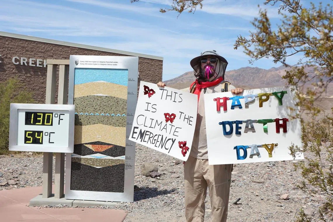 A protester stands next to a digital display of an unofficial heat reading in Death Valley, California. 