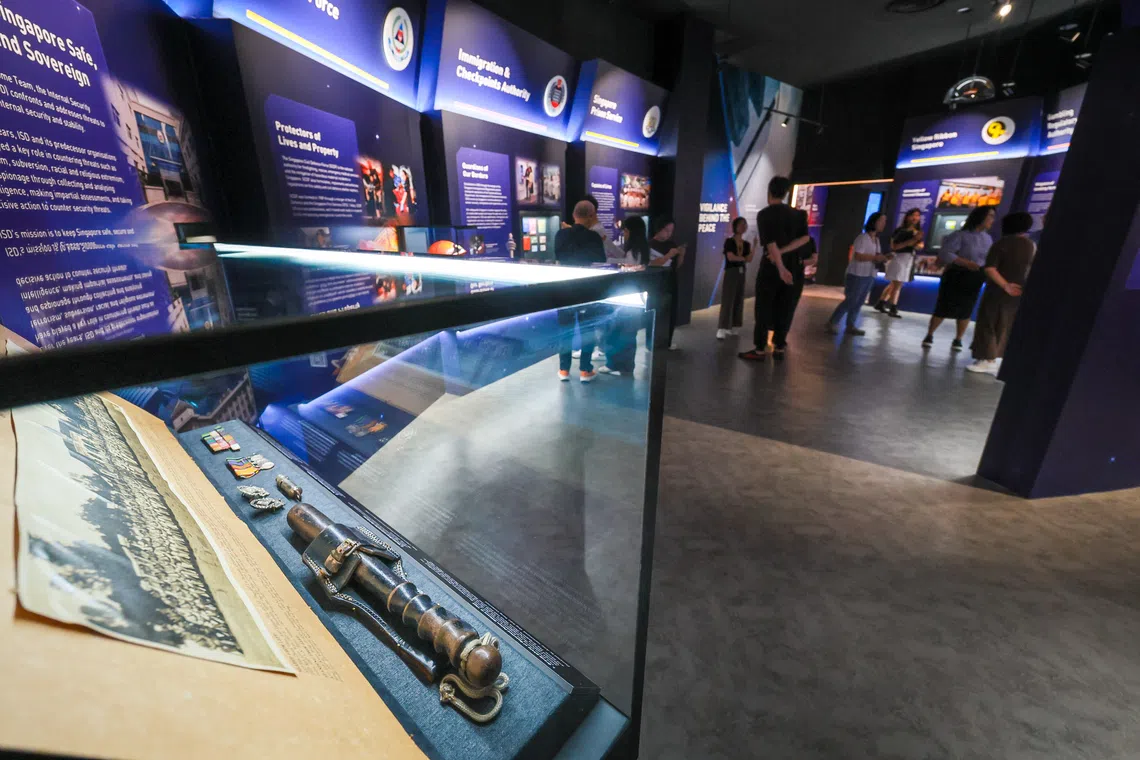 An old wooden police baton and other historical police equipment are displayed at the Home Team Gallery.