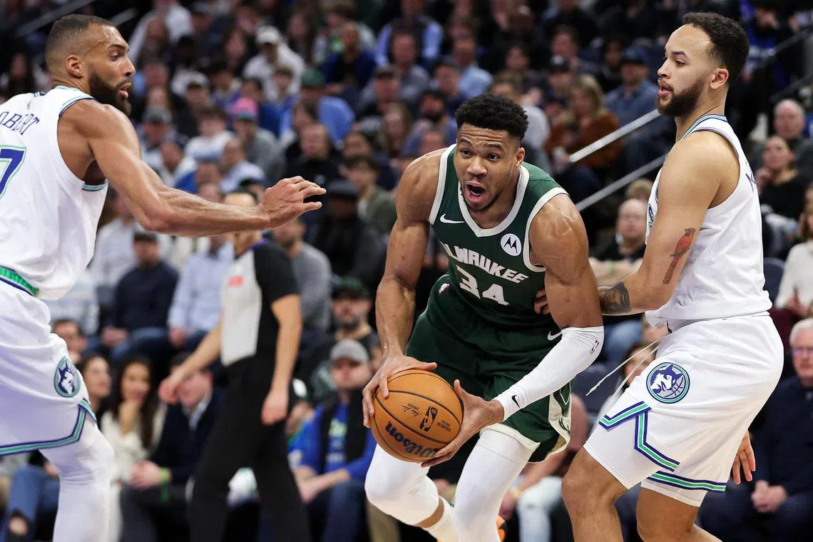 Milwaukee Bucks forward Giannis Antetokounmpo  works around Minnesota Timberwolves forward Kyle Anderson and centre Rudy Gobert during the first half at Target Centre.