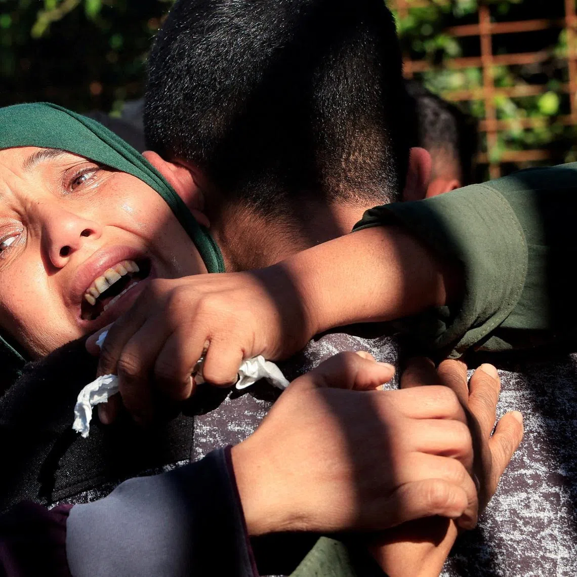 Mourners hug each other during the funeral of Palestinians who, according to medics, were killed in an Israeli strike on Sunday, at Nasser Hospital in Khan Younis, southern Gaza Strip, January 11, 2026. REUTERS/Haseeb Alwazeer
