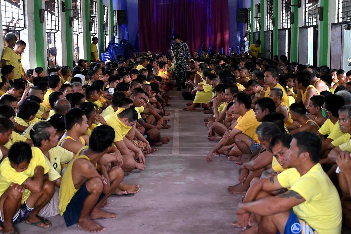 TOPSHOT - Prison inmates sit inside a compound chapel as police conduct a search operation in the cells for contraband and illegal drugs at the Manila City Jail in Manila on October 21, 2022. (Photo by JAM STA ROSA / AFP)