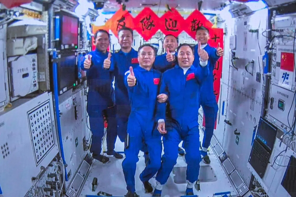 Astronauts Fei Junlong (front left), Zhang Lu (back left) and Deng Qingming (back, second from left) take photos with the crew of the Shenzhou-16 spaceflight mission inside the Chinese space station core module Tianhe on May 30.