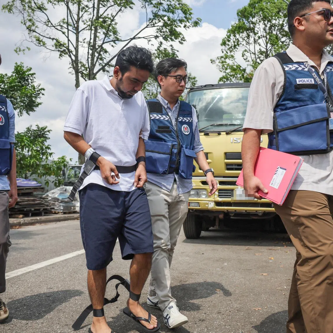 Mohd Mazuan Abdullah being escorted by police officers along Sungei Kadut street 4 to retrace his steps in a vehicle theft and car cloning syndicate in Malaysia, on March 23.