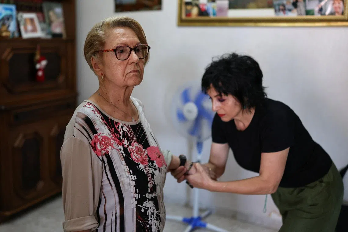 Piera Pomente, coordinator of the support desk for the scheme at a local pharmacy, checking the bracelet worn by Dina Gazzella.