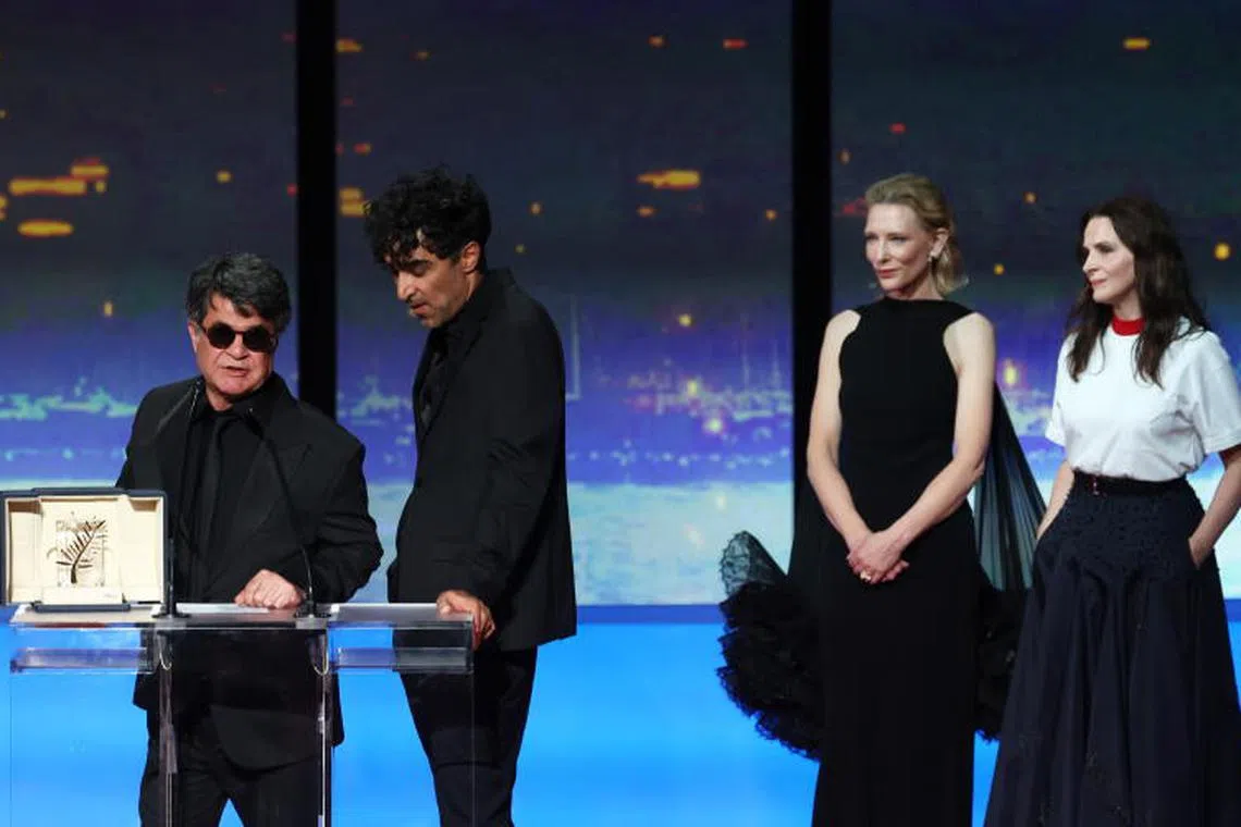 epa12132936 Iranian director and screenwriter and producer Jafar Panahi (L) speaks on stage after winning the Palme d'Or for the film "Un simple accident" (A Simple Accident) watched by Juliette Binoche (R) and Cate Blanchett (2-R) during the closing and awards ceremony of the 78th annual Cannes Film Festival, in Cannes, France, 24 May 2025. The film festival runs from 13 to 24 May 2025. EPA-EFE/MOHAMMED BADRA
