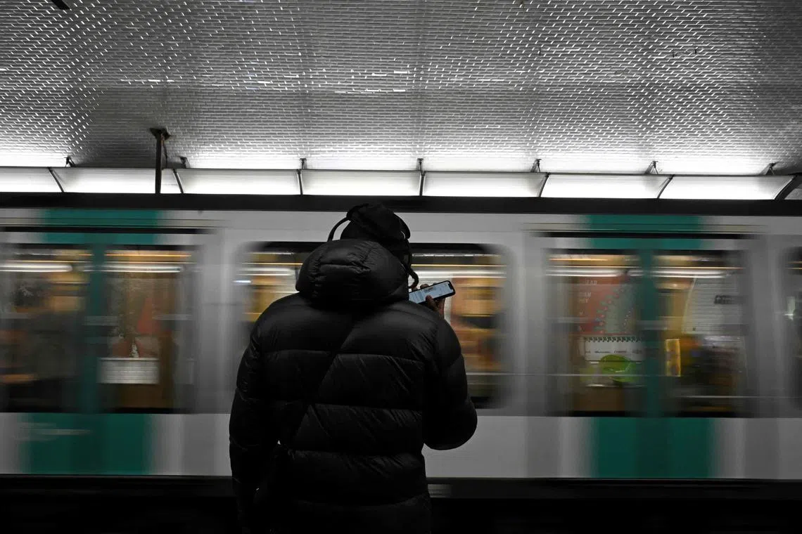 A person standing on the platform of a metro station in Paris.
