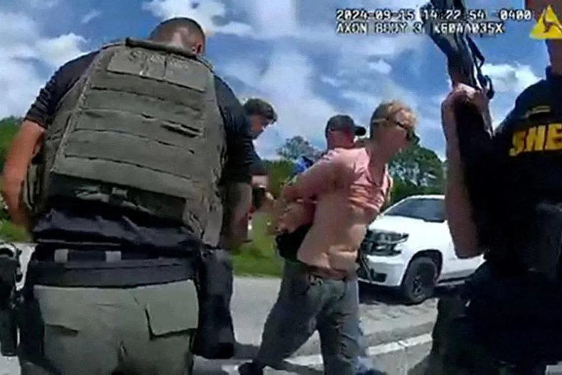 Ryan Routh, who is suspected of attempting to assassinate Republican presidential nominee and former U.S. President Donald Trump at his West Palm Beach golf course, is led by two Martin County Sheriff's Office deputies after his arrest near Palm City, Florida on Sept15. 