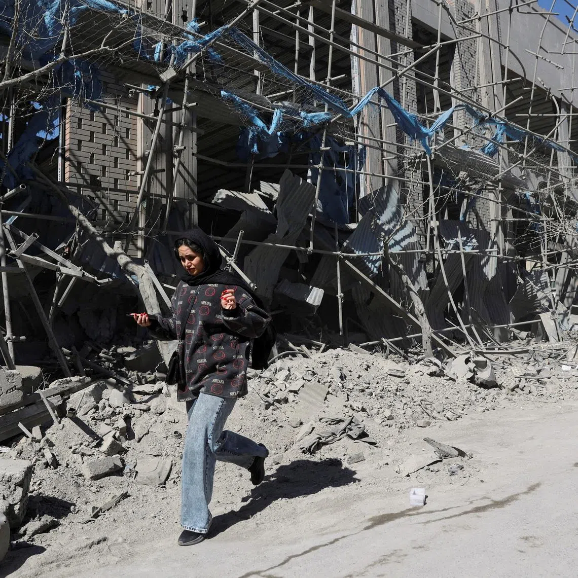 A woman walks on the street following an Israeli and US strike on a police station, amid the US-Israeli conflict with Iran, in Tehran, Iran, on March 3.