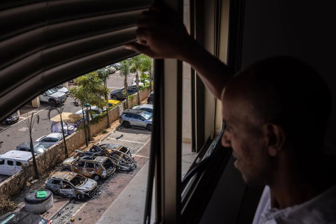 From the window of his familyÕs apartment, Aweke Zena surveys damage from a rocket from Gaza that struck a parking lot in Ashkelon, Israel on Saturday, Oct. 7, 2023. Israel and Gaza were at war on Saturday after Palestinian militants launched an early morning assault on southern Israel that had few precedents in its complexity and scale, invading several Israeli towns and firing thousands of rockets toward cities as far away as Jerusalem. (Tamir Kalifa/The New York Times)