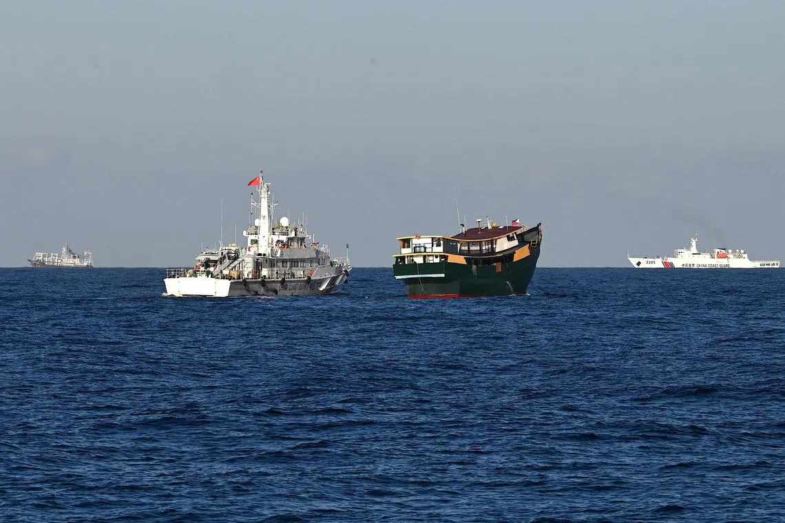 A China Coast Guard vessel (centre left) sailing near the Philippine military-chartered Unaizah May 4 (centre right) during its supply mission to Second Thomas Shoal in the disputed South China Sea on March 5, 2024.