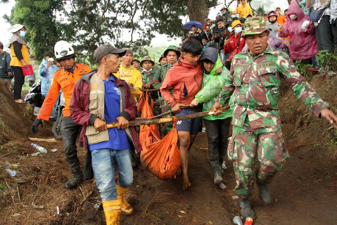 Indonesian rescue teams carry the body of a Mount Marapi eruption victim.