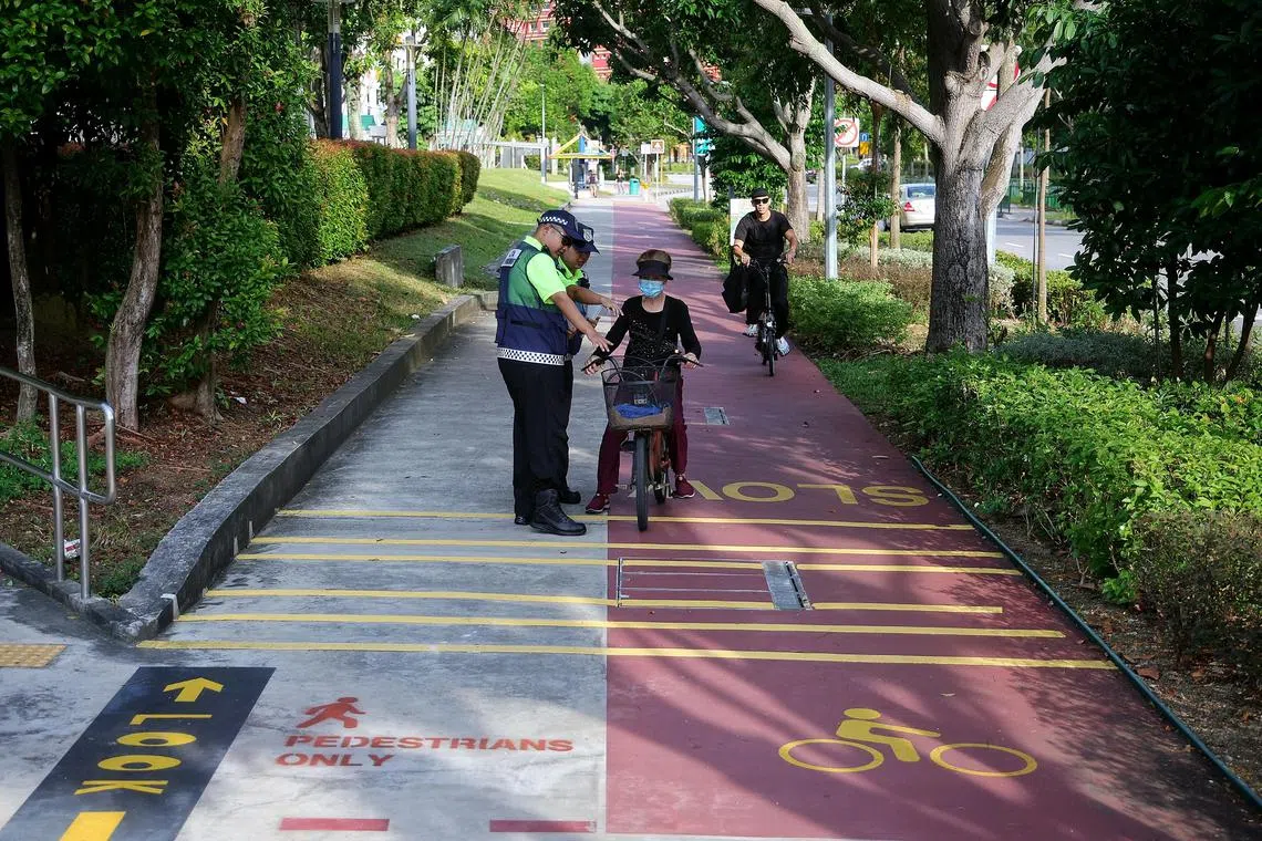 LTA?s active mobility enforcement officers (AMEOs) advising cyclists to keep to their lane next to a newly converted 200m-long pedestrian-only path in Tampines on July 1, 2025. ST PHOTO: KEVIN LIM vcpath01