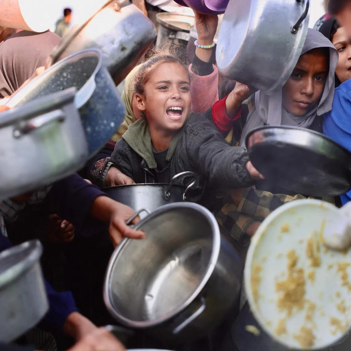 Displaced Palestinians gather to receive donated food portions at a charity kitchen in Khan Yunis in the southern Gaza Strip on Dec 17, 2025. 