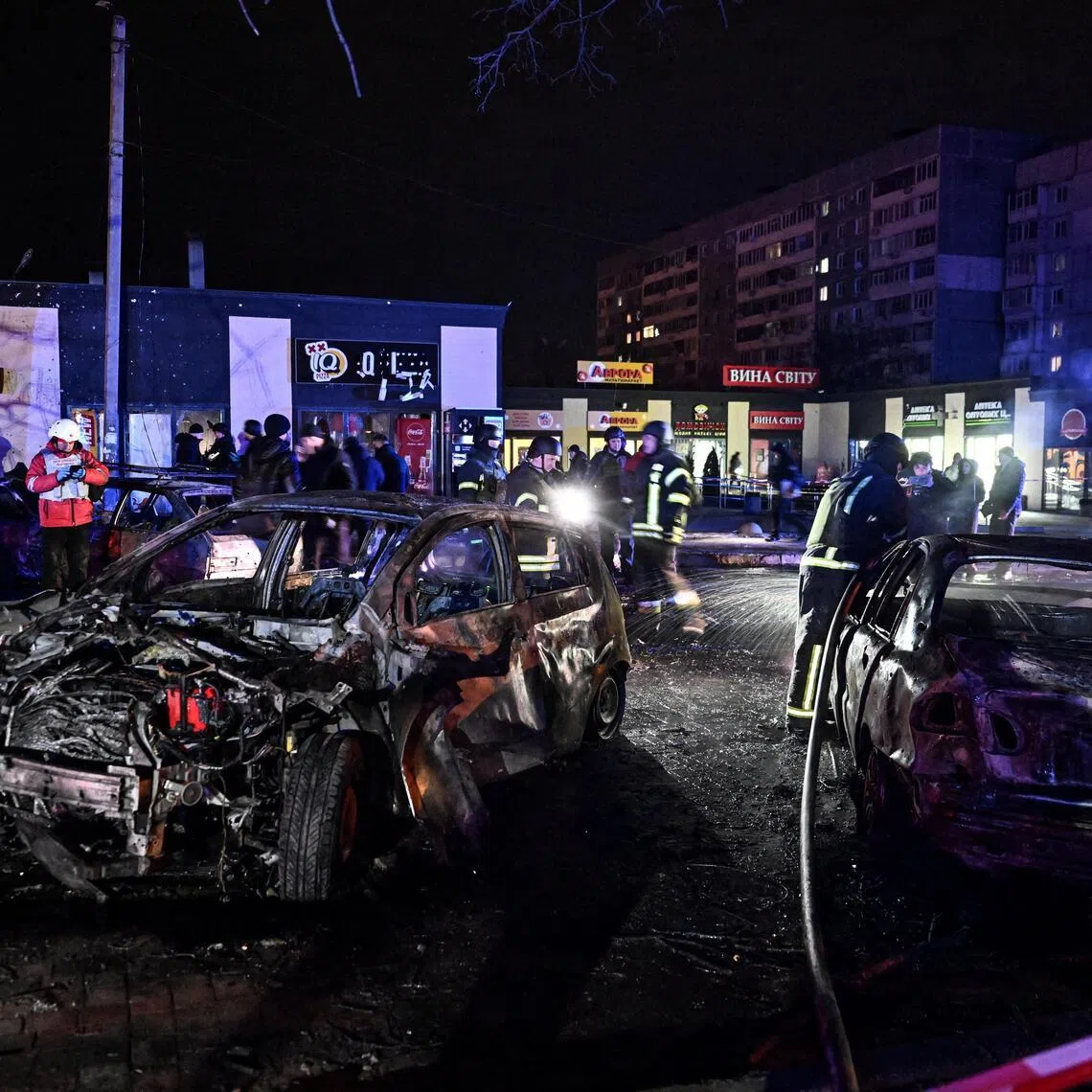 Firefighters working next to cars destroyed by a Russian drone strike, in the Ukrainian city of Zaporizhzhia on Feb 3.