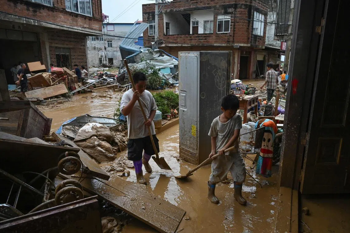 Children help to clean mud from their house, which was flooded when the Liulan reservoir collapsed on July 6.