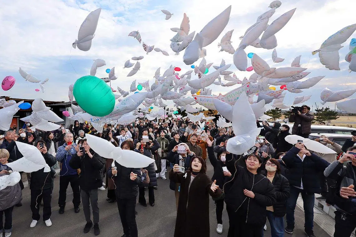TOPSHOT - People release dove-shaped balloons in the air in remembrance in Natori, Miyagi Prefecture, on March 11, 2025, to mark the 14th anniversary of the magnitude 9.0 earthquake which triggered a tsunami and nuclear disaster. (Photo by JIJI PRESS / AFP) / Japan OUT