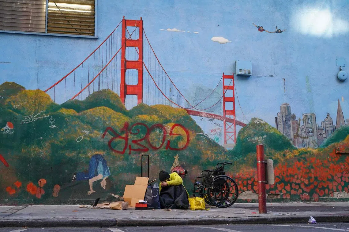 A homeless person lies against a mural of the Golden Gate Bridge near APEC Summit headquarters on November 11, 2023 in downtown San Francisco, California. The city took steps to clean up in advance of the APEC Summit, currently taking place through November 17. (Photo by Loren Elliott / AFP)