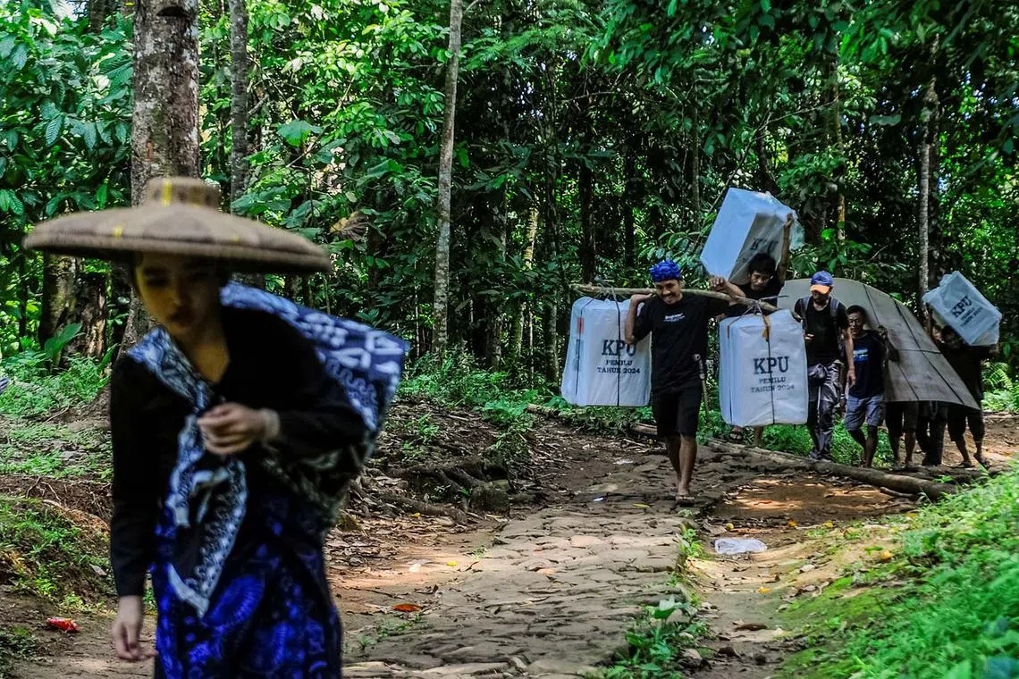 Baduy men carrying ballot boxes for distribution to polling stations centre ahead of the presidential election at Kanekes village in Lebak, Banten province, Indonesia, Feb 13, 2024.