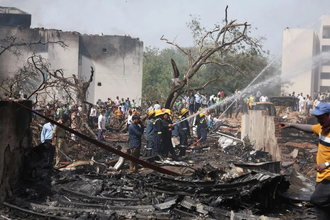 FILE PHOTO: People gather near a damaged building and trees as firefighters work at the site where an Air India plane crashed in Ahmedabad, India, June 12, 2025. REUTERS/Amit Dave/File Photo