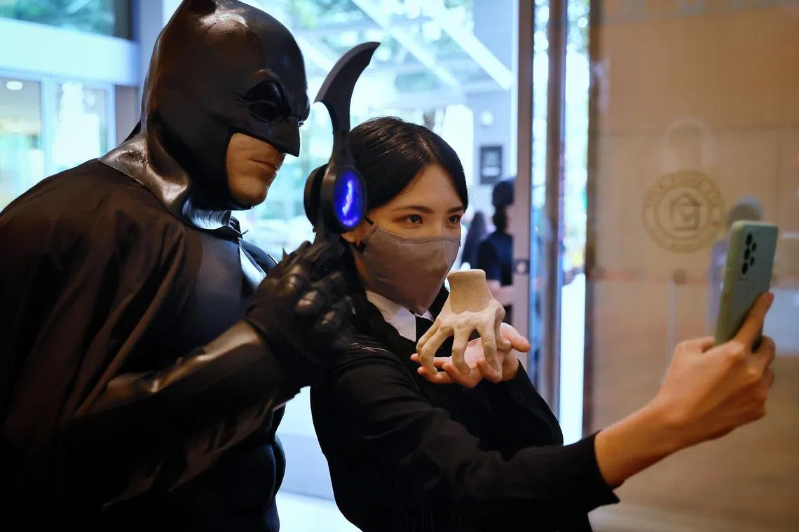 Cosplayers dressed as comic character Batman and television character Wednesday Addams take a photograph together outside the Singapore Comic Con at the Sands Expo & Convention Centre on Sunday (Dec 11, 2022). 