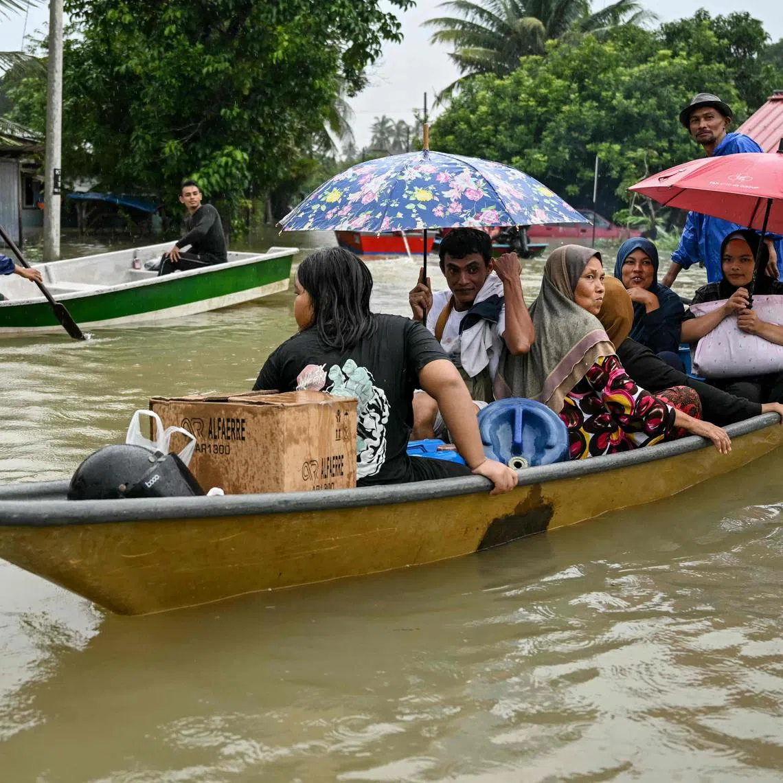 Residents are transported on boats through flood waters after days of heavy rain in Tumpat in Malaysia's Kelantan state on November 30, 2024.