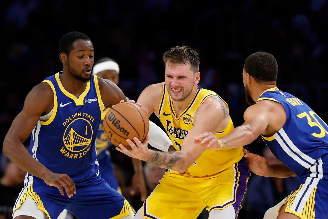 Luka Doncic of the Los Angeles Lakers is trapped by Jonathan Kuminga (No. 1) and Stephen Curry of the Golden State Warriors in the fourth quarter of the game at Crypto.com Arena.