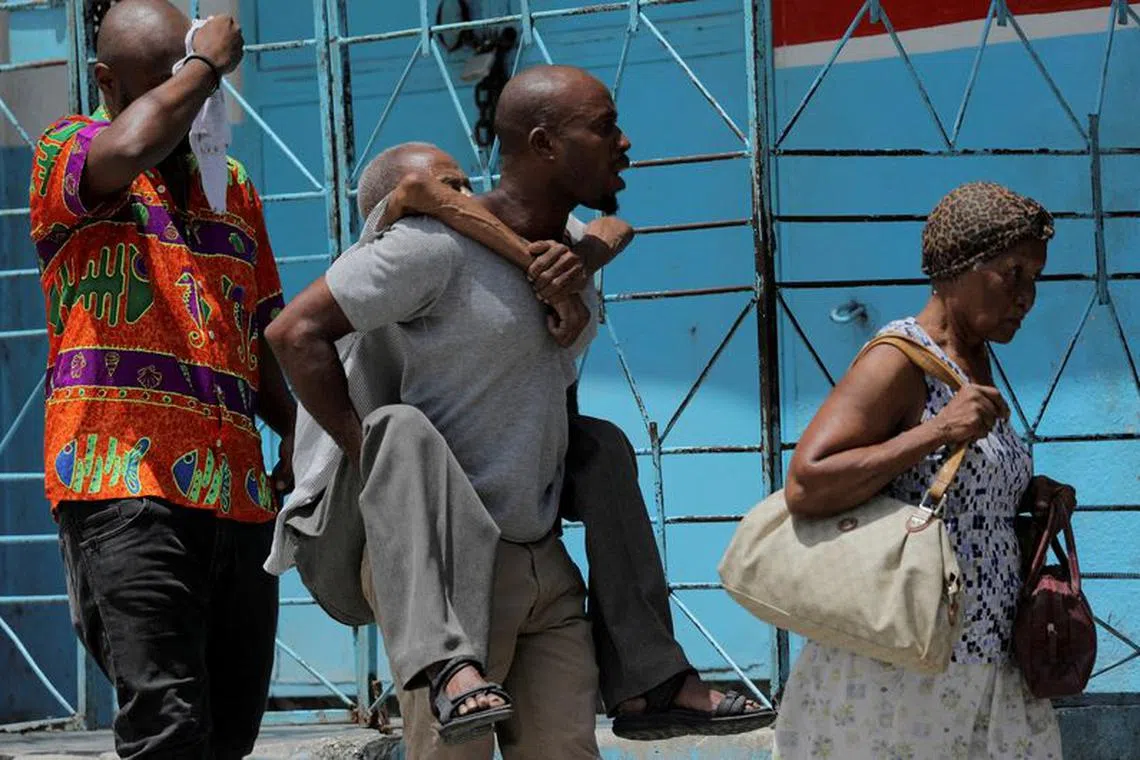 FILE PHOTO: man carries an elderly man as they flee their neighbourhood Carrefour Feuilles after gangs took over, in Port-au-Prince, Haiti August 15, 2023. REUTERS/Ralph Tedy Erol/File Photo