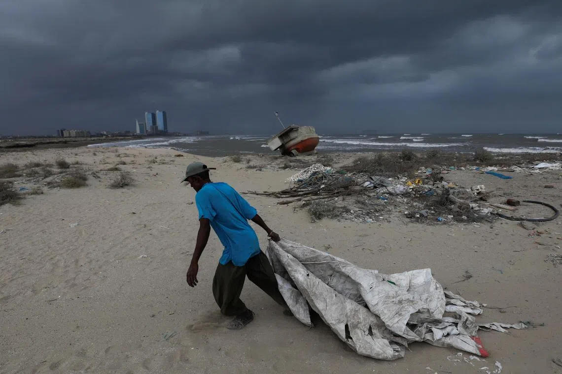 Sooraj, 32, a fisherman and diver, pulls a sheet to cover his belongings before the arrival of Cyclone Biparjoy, in Karachi, Pakistan.