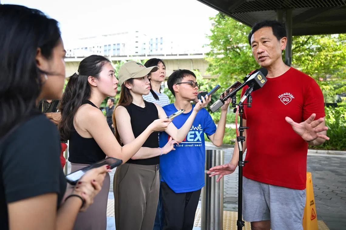 Health Minister Ong Ye Kung (right) speaking to the media on the sidelines of a community mass brisk walk event at Bukit Canberra on April 27.