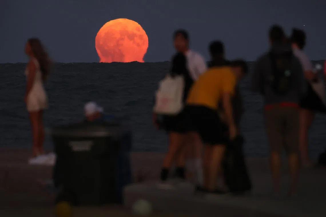 People gathering along North Avenue Beach as a super blue moon rises on Aug 30, 2023, in Chicago, Illinois. The super blue moon is not expected to appear again until 2037. 