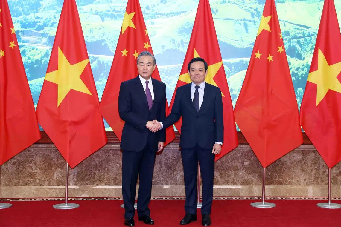 Chinese Foreign Minister Wang Yi (L) shaking hands with Vietnamese Deputy Prime Minister Tran Luu Quang ahead of their meeting in Hanoi on Dec 1. 