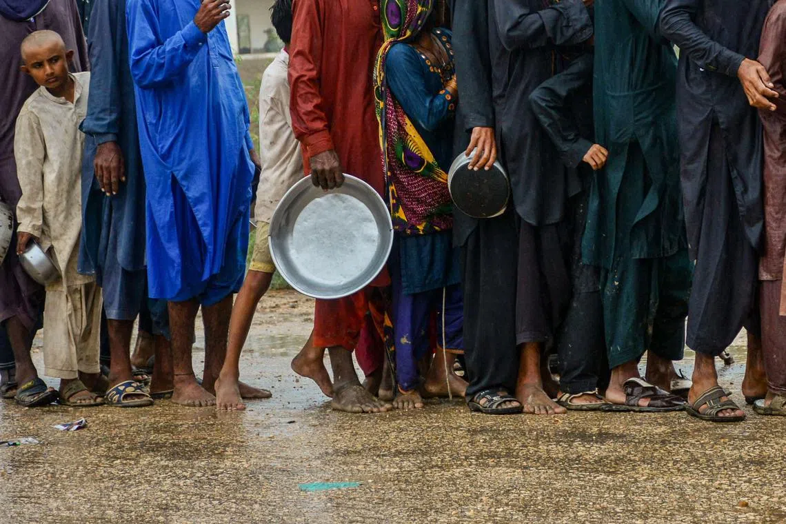 Cyclone evacuees wait to receive food near a temporary shelter set at a school in a coastal area in Sujawal of Pakistan's Sindh province on June 15, 2023. Howling gales and crashing waves pounded the coastline of India and Pakistan on June 15, in the hours counting down to the landfall of a powerful cyclone that has prompted mass evacuations. (Photo by Akram SHAHID / AFP)