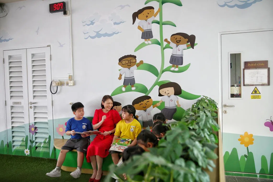 Greenwood Primary pupils reading books with principal Mrs Tricilia Chua at a multipurpose corner in school.